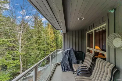 a porch with two chairs and a balcony with trees at Best ski in ski out condo #3 in Aspens in Whistler