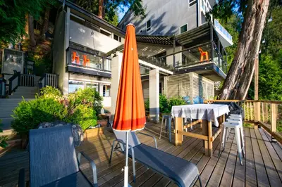 a patio with two umbrellas and a table and chairs at SALT COTTAGE Waterfront Guest House with Superb Views in West Vancouver