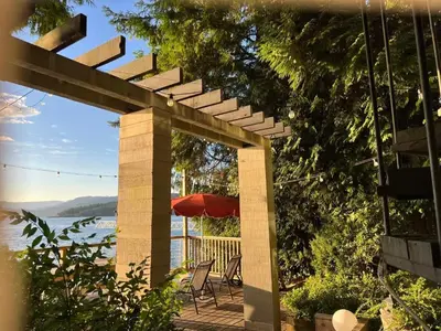 a patio with an umbrella and a table and chairs at SALT COTTAGE Waterfront Guest House with Superb Views in West Vancouver