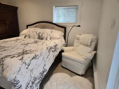 a bedroom with a bed and a chair and a lamp at Private master bedroom in a farmhouse in Nanoose Bay