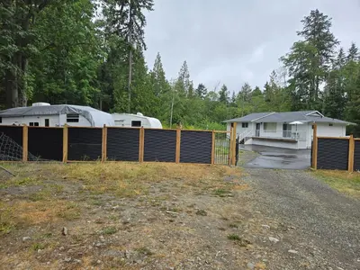 a yard with a fence and a house at Private master bedroom in a farmhouse in Nanoose Bay