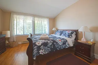 a bedroom with a bed with a floral bedspread at Iconic 3-Story Waterfront 'Marina House' w/ View in Gibsons