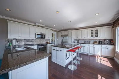 a kitchen with white cabinets and a island with red bar stools at Iconic 3-Story Waterfront 'Marina House' w/ View in Gibsons