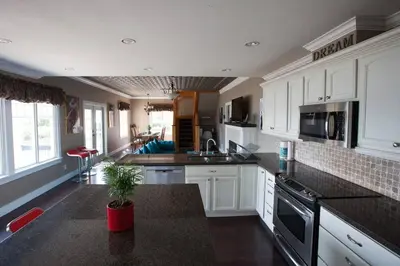 a kitchen with white cabinets and a black counter top at Iconic 3-Story Waterfront 'Marina House' w/ View in Gibsons