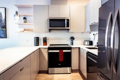 a kitchen with stainless steel appliances and white cabinets at Monashee Sunshine - Condo with Private Hot Tub in Revelstoke