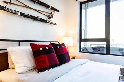 a bedroom with a bed with red and black pillows at Monashee Sunshine - Condo with Private Hot Tub in Revelstoke