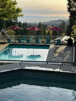 a swimming pool with chairs and umbrellas at The Lions Self Contained Suite, Shared Pool, Hot Tub, Views in North Vancouver
