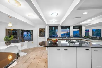 a large kitchen with white cabinets and a table at Grouse Cheerful large private bedroom, bath, shared deck, pool, hot tub in North Vancouver