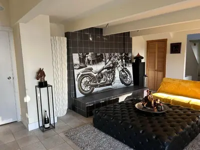 a living room with a couch and a motorcycle on the wall at Grouse Cheerful large private bedroom, bath, shared deck, pool, hot tub in North Vancouver