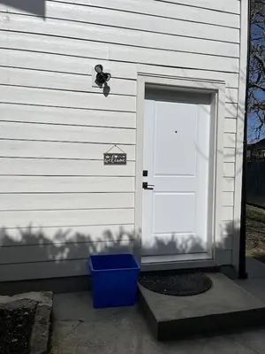 a door to a house with a blue bin next to it at Dugg Bed And Breakfast in Victoria