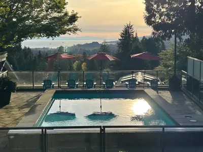 a swimming pool with chairs and umbrellas at Seymour Private Bedroom, Ensuite Bathroom with Shared Pool, Hot Tub with Views in North Vancouver
