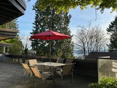 a table with a red umbrella on a patio at Seymour Private Bedroom, Ensuite Bathroom with Shared Pool, Hot Tub with Views in North Vancouver