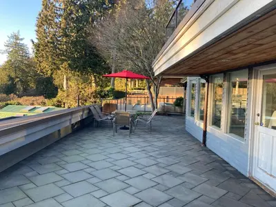 a patio with a table and chairs and an umbrella at Seymour Private Bedroom, Ensuite Bathroom with Shared Pool, Hot Tub with Views in North Vancouver