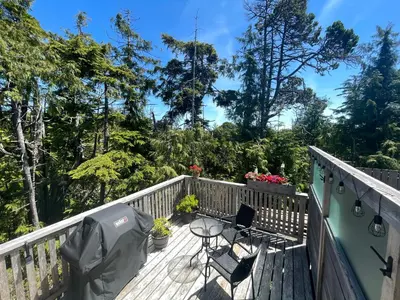 a deck with two chairs and a table on it at Brown's Beach Guest Suite in Ucluelet