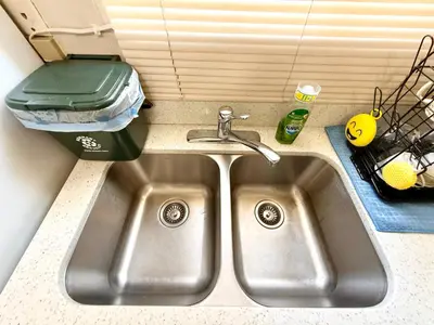 a stainless steel kitchen sink with a trash can next to it at Burnaby Metrotown Cozy 3 Bedroom Suite Walk to Skytrain and Malls in Burnaby