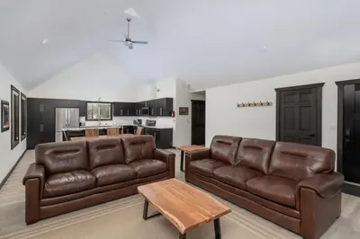 a living room with two brown leather couches and a kitchen at The Sundance Cabin in Valemount