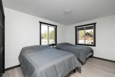 two beds in a room with two windows at The Sundance Cabin in Valemount