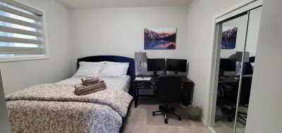 a bedroom with a bed and a desk with a computer at Delightful 1-bedroom Private Suite in a New Home in Calgary