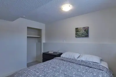 a bedroom with a bed and a dresser with a nightstand at 2bedroom suite w/ great access into & out the city - 7818 in Calgary