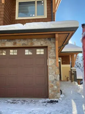 a brown garage door with snow on top of it at Cozy Modern Ski-in & Ski-out, Hot Tub, Townhouse in Sun Peaks