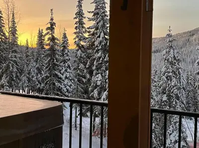 a view from a balcony with snow covered trees at Cozy Modern Ski-in & Ski-out, Hot Tub, Townhouse in Sun Peaks