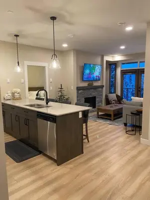 a kitchen with a sink and a living room at Cozy Modern Ski-in & Ski-out, Hot Tub, Townhouse in Sun Peaks