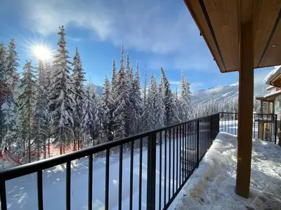 a balcony of a house with snow covered trees at Cozy Modern Ski-in & Ski-out, Hot Tub, Townhouse in Sun Peaks