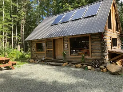 a wooden cabin with solar panels on the roof at Mini Moo-light Cabin in Clearwater