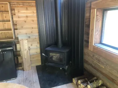a wood stove in a room in a log cabin at Mini Moo-light Cabin in Clearwater