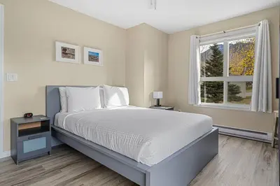a white bedroom with a large bed and a window at Polar Peaks Hot Tub Pool Gas Fireplace in Radium Hot Springs