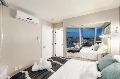 a bedroom with two beds and a large window at Vancouver Nest Downtown 2BR near Rogers Arena in Vancouver