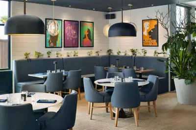 a dining room with tables and blue chairs at Four Points by Sheraton Penticton at the Convention Centre in Penticton