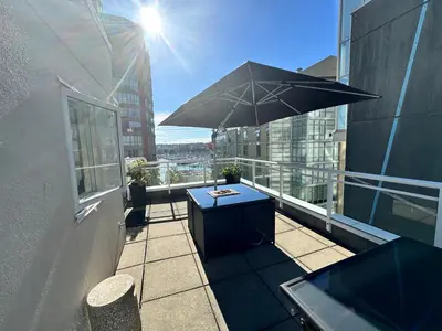 a balcony with a table and an umbrella on a building at Penthouses of Beach Ave in Vancouver