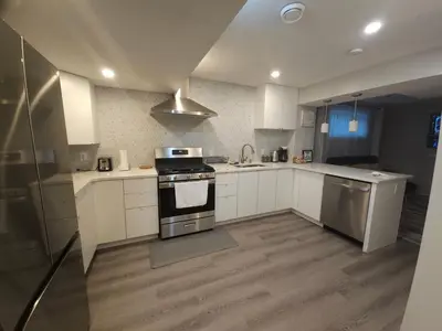 a kitchen with white cabinets and a stove top oven at Cozy 2 Bedroom Suite, Queen Beds, Near the Airport in Edmonton