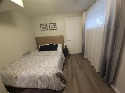 a bedroom with a bed and a large window at Cozy 2 Bedroom Suite, Queen Beds, Near the Airport in Edmonton