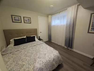 a bedroom with a large bed and a window at Cozy 2 Bedroom Suite, Queen Beds, Near the Airport in Edmonton