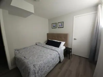 a small bedroom with a bed and a door at Cozy 2 Bedroom Suite, Queen Beds, Near the Airport in Edmonton