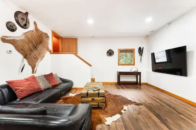 a living room with a leather couch and a table at Gem by Manning Park: Luxury Loghouse “Ravenloft” in Sunshine Valley
