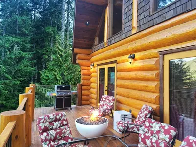 a deck with chairs and a fire pit on a cabin at Gem by Manning Park: Luxury Loghouse “Ravenloft” in Sunshine Valley